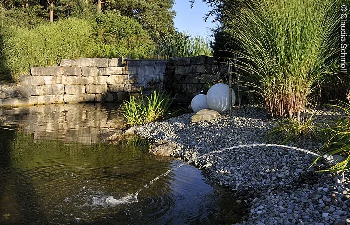Ein kleiner Teich mit Springbrunnen und Begrünung auf dem Spiel-Golf-Park Amigo.