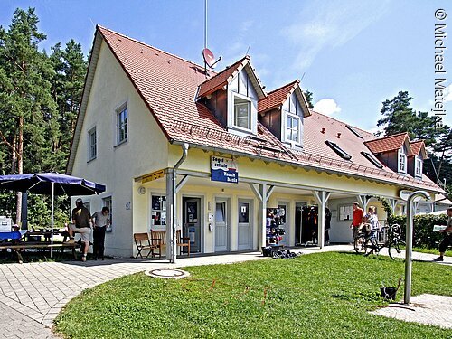 Das weiße Haus der Segelschule Greubel. Davor ein kleiner Hof mit grüner Wiese.