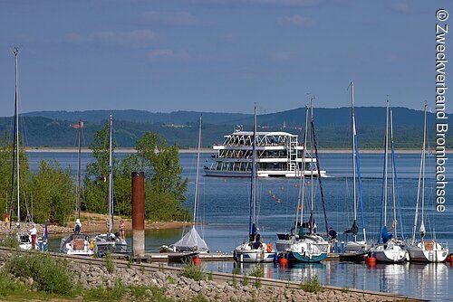 Blick auf einen Teil des Segelhafens in Absberg. Im Hintergund fährt das Personenschiff MS Brombachsee über den Brombachsee.