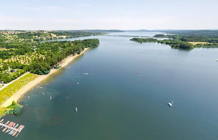 Luftbild des kleinen Brombachsees. Blaues Wasser. Links am grünen Ufer ein kleiner Segelhafen.