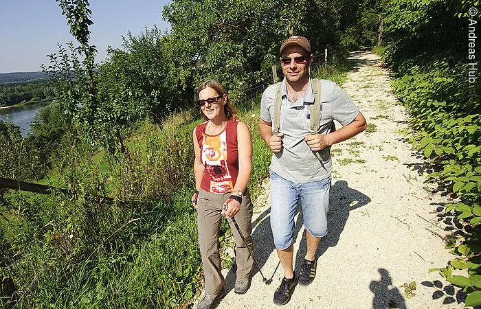 Zwei Wanderer auf dem Mühlenweg bei Absberg. Der Mühlenweg führt durch grüne Landschaften vorbei an einem See.