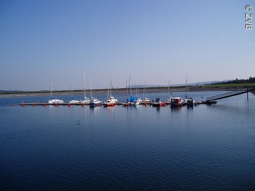 Ein Segelhafen im blauen See. Nur wenige Boote liegen im Hafen.